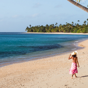 A girl walking on a tropical beach in a sarong