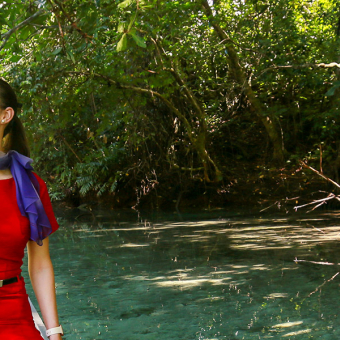 A lady in a red dress sitting on a kayak in a river in Samoa